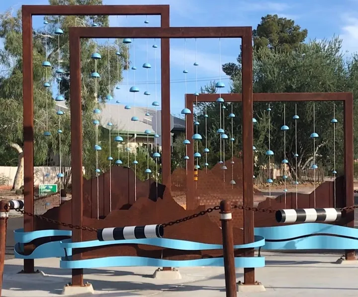 Marcos de acero color óxido con piezas de cerámica azul colgantes en una intersección de Third Street