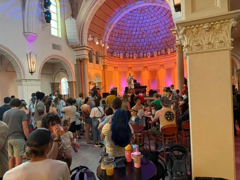 Neighbors fill La Rosa's former chapel for the Midtown Ice Cream Social as a musician plays on the stage under the dome
