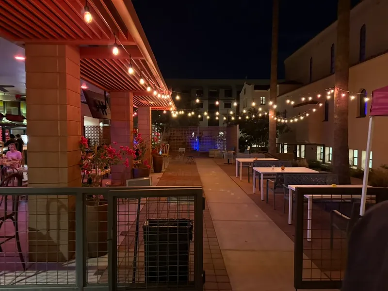 El patio de Sisters de noche, con luces colgantes, el antiguo monasterio a la derecha y los nuevos apartamentos al fondo