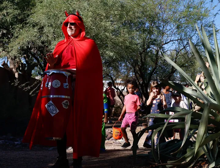 Un vecino disfrazado de diablo rojo reparte dulces a niños en el Pocket Park