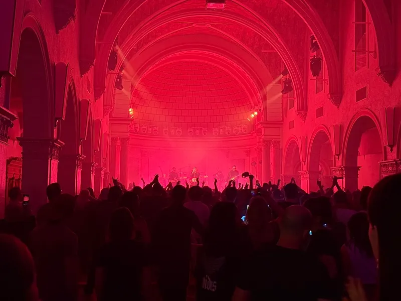 Un concierto en La Rosa, con el público bajo los arcos de la antigua capilla iluminada de rosa